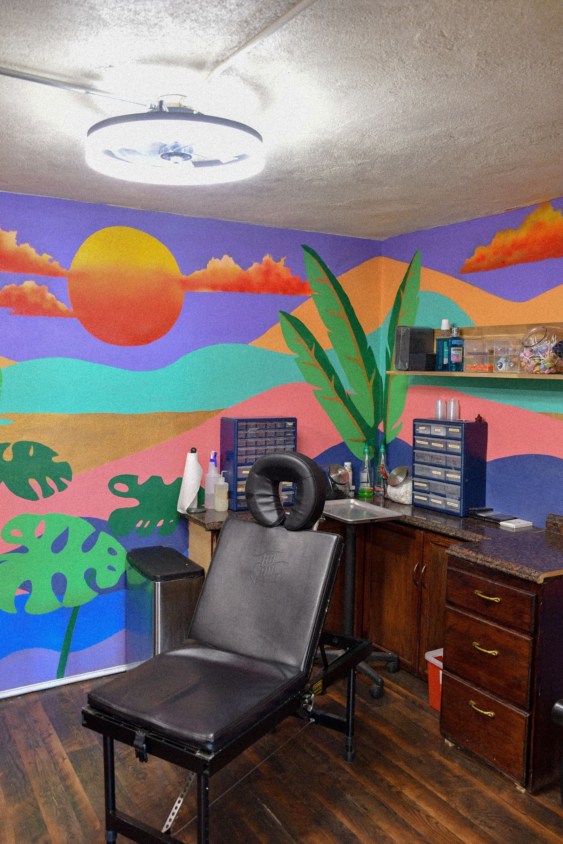 Piercing room at American Gypsy Tattoo with a vibrant landscape mural